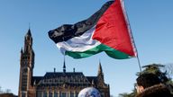 Protesters hold a Palestinian flag as they gather outside the International Court of Justice (ICJ) , in The Hague. Pic: Piroschka van de Wouw/Reuters