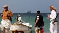 Armed men stand on the beach as the Galaxy Leader commercial ship, seized by Yemen&#39;s Houthis last month, is anchored off the coast. File pic