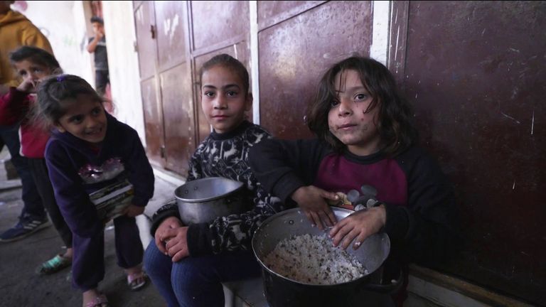 Two girls eat plain rice on the floor in Gaza