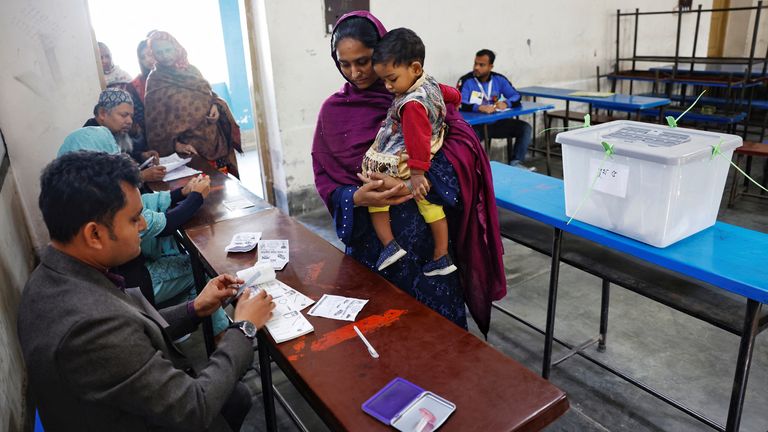 A woman carries her child while casting her vote at the Dhaka Residential Model College voting centre, during the 12th general election in Dhaka, Bangladesh, January 7, 2024. REUTERS/Mohammad Ponir Hossain