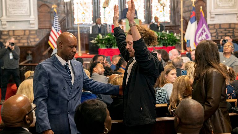 A protester against the Israel-Hamas war who chanted "cease-fire now," raises his arms while being removed from the venue as President Joe Biden delivers his speech at Mother Emanuel AME Church, where nine worshippers were killed in a mass shooting by a white supremacist in 2015 in Charleston, S.C., Monday, Jan. 8, 2024.  (AP Photo/Mic Smith)