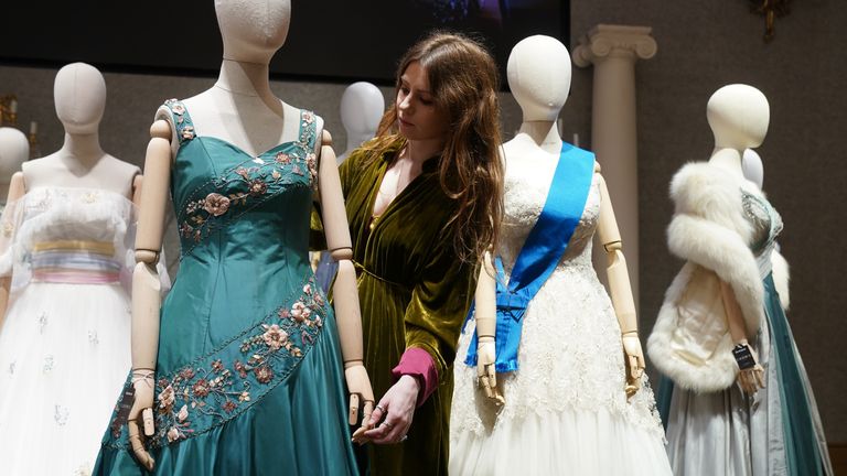 A gallery assistant adjusts a replica of a gown worn by Queen Elizabeth II, which is part of the collection of more than 450 costumes, sets and props from the Netflix series The Crown, on show at Bonhams in central London, ahead of being auctioned next month. Picture date: Tuesday January 9, 2024.

