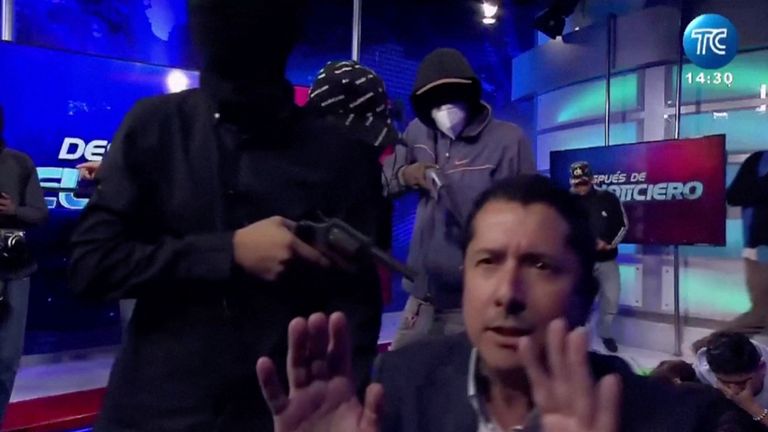 Hooded man points a gun at Ecuadorian TV presenter Jose Luis Calderon. Pic: TC television station