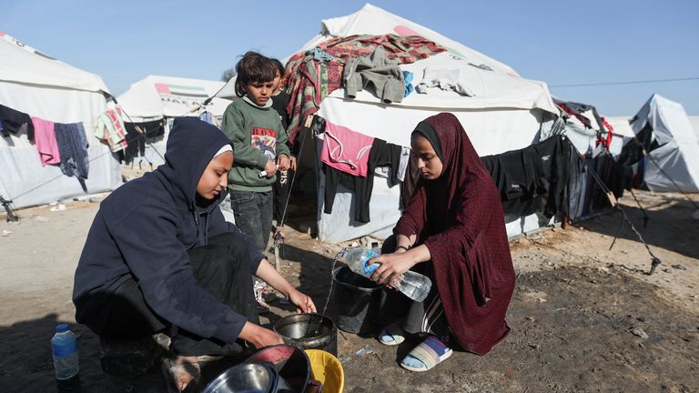 Young girls use bottled water to wash in a tent camp in Rafah, southern Gaza