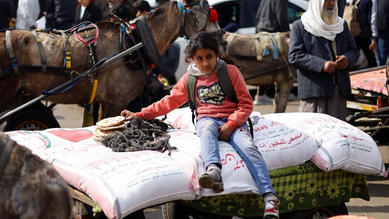 A Palestinian girl sits on bags of flour distributed by the UNRWA in Gaza