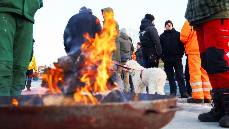 German farmers warm themselves near a fire as they block access to highway A10 during a protest against the cut of vehicle tax subsidies of the so-called German Ampel coalition government, in Birkenwerder, Germany, January 8, 2024. REUTERS/Fabrizio Bensch