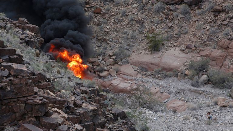 文件 - 2018 年 2 月 10 日，亚利桑那州大峡谷锯齿状岩石上发生致命旅游直升机坠毁事故，一名幸存者（右下）离开现场。  2024 年 1 月 5 日星期五，内华达州一名法官批准向一名英国游客的父母提供 1 亿美元的现金和解，该游客是 2018 年直升机在大峡谷坠毁并起火时遇难的五人之一，其中包括他的新婚妻子.（泰迪藤本来自美联社，文件）