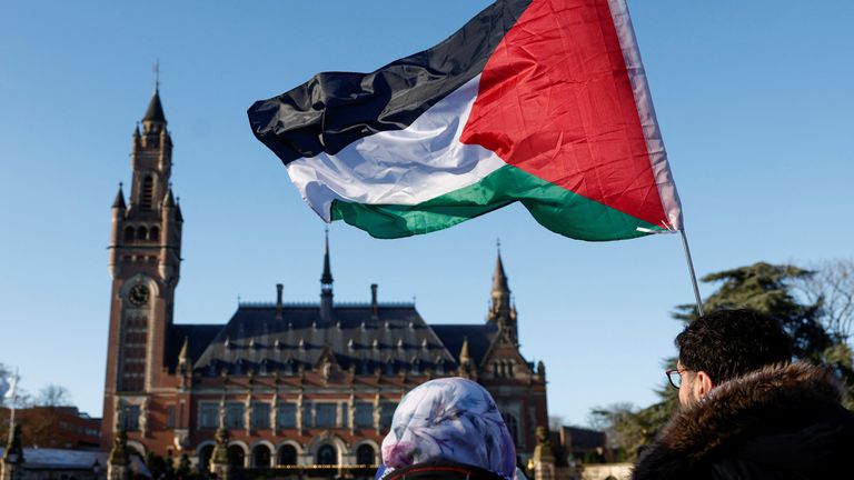 Protesters hold a Palestinian flag as they gather outside the International Court of Justice (ICJ) , in The Hague. Pic: Piroschka van de Wouw/Reuters