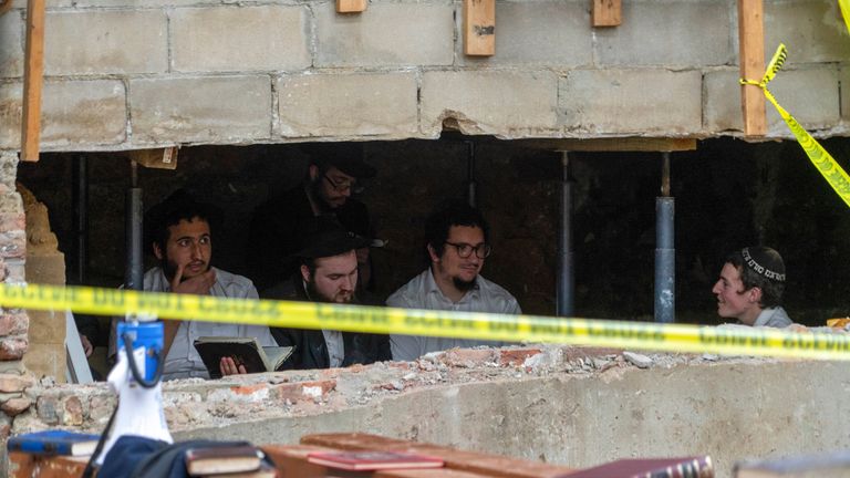 Hasidic Jewish students sit behind a breach in the wall of a synagogue that led to a tunnel dug by the students 
Pic:AP