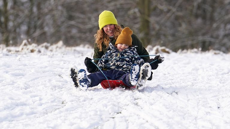 A mother and son sledging on the snow in Tatton Park, Cheshire