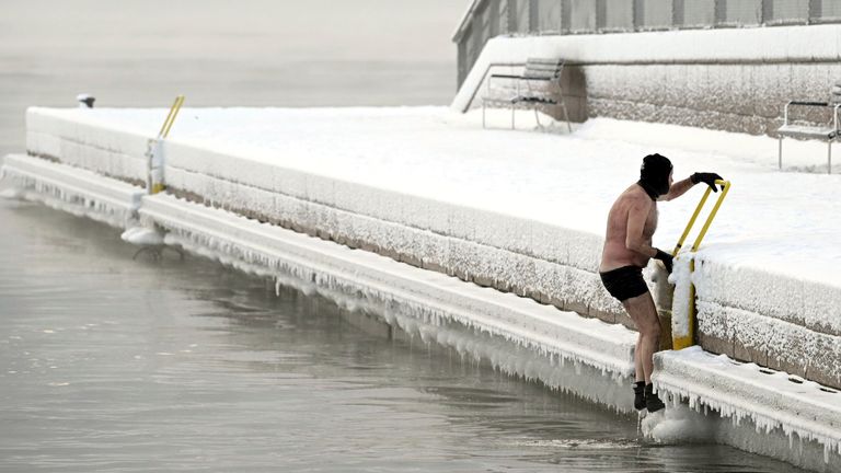 A man climbs out from the icy sea to a pier in southern Helsinki