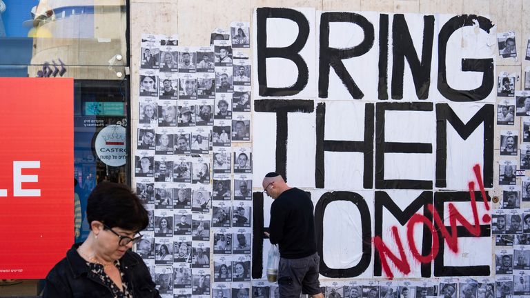 People walk past a wall with photographs of hostages, mostly Israeli civilians who were abducted during the Oct. 7, unprecedented Hamas attack on Israel, in Tel Aviv, Israel, Friday, Jan. 19, 2024. (AP Photo/Oded Balilty)