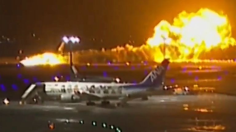 The Japan Airlines plane is seen on fire on the runway. Pic: AP
