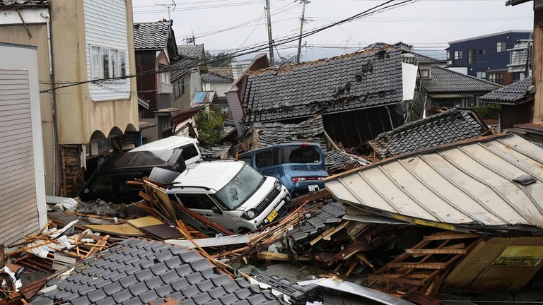 Vehicles and collapsed houses are seen in an area hit by a fire, following earthquakes in Suzu, Ishikawa prefecture, Japan Wednesday, Jan. 3, 2024. A series of powerful earthquakes that hit western Japan left multiple people dead Wednesday, as rescue workers fought to save those feared trapped under the rubble of collapsed buildings.(Kyodo News via AP)