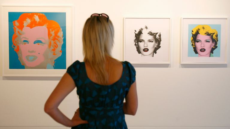An woman looks at "Marilyn 29" (L) by artist Andy Warhol and "Kate Moss (Black)" and "Kate Moss (Yellow)" by Banksy, part of the exhibition Warhol vs Banksy at The Hospital in Covent Garden, London, August 9, 2007. It is the first joint exhibition of the two artists and runs until September 1, 2007. REUTERS/Luke MacGregor (BRITAIN)
