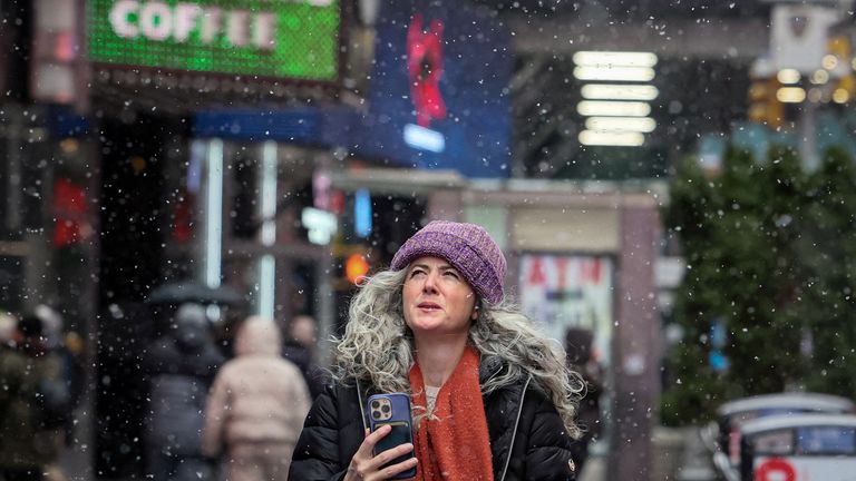 People walk through Times Square as the snow falls during a winter storm in New York City, U.S., January 19, 2024. REUTERS/Brendan McDermid