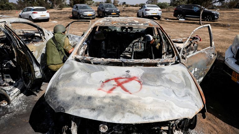 Israeli soldiers inspect a burnt car at the Nova Festival on 13 October: Pic: Reuters
