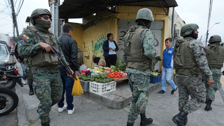 Soldiers patrol the perimeter of Inca prison during a state of emergency as a food vendor works on the sidewalk in Quito, Ecuador, Tuesday, Jan. 9, 2024. Pic: AP