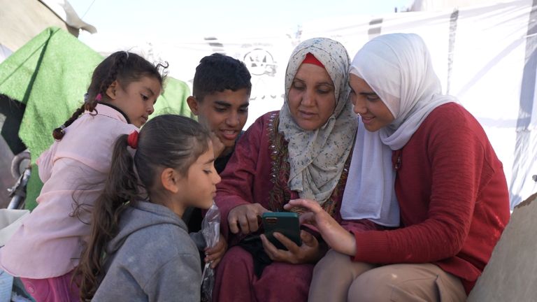 Duaa, her mother and siblings look at photos from before the war