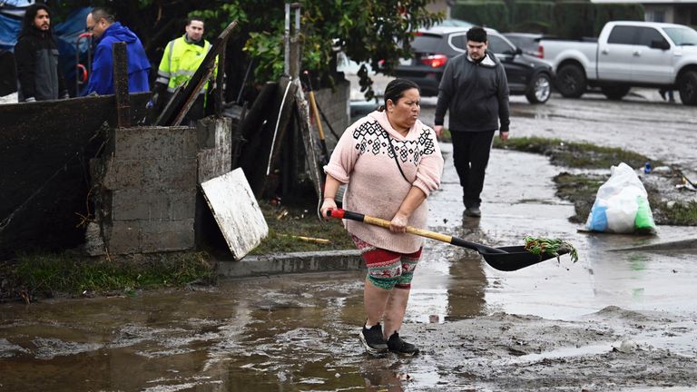A woman removes debris from floods during a rain storm 
Pic: AP 