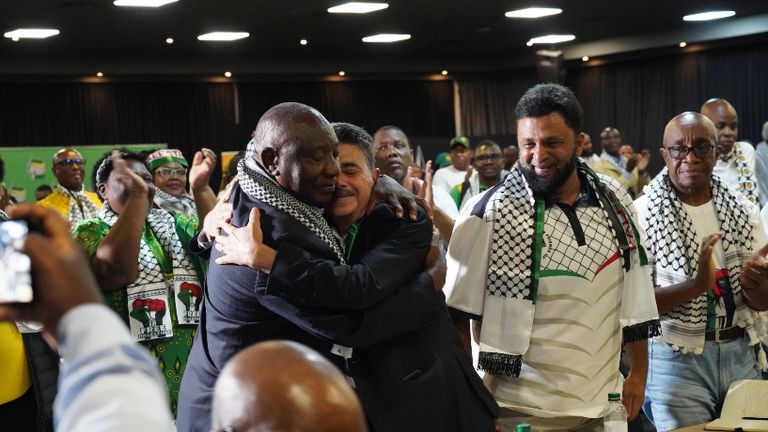 South African President Cyril Ramaphosa, left, hugs the Palestinian deputy ambassador Bassam Elhussiny after the ruling
