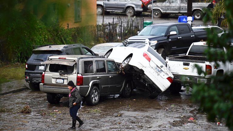 A woman walks by cars damaged by floods during a rainstorm in San Diego
Pic: AP