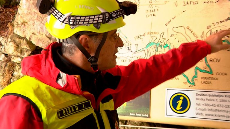 In this photo taken from video, a rescuer inspects the map of Krizna Jama cave near Grahovo, Slovenia, Sunday, Jan. 7, 2024. Slovenian authorities say five people are trapped in a cave in the southwest of the country because of high water levels caused by heavy rainfall. The group includes a family of three and two guides who have been stuck in the Krizna Jama cave since Saturday when water levels rose inside, blocking the way out. (Pop TV via AP)