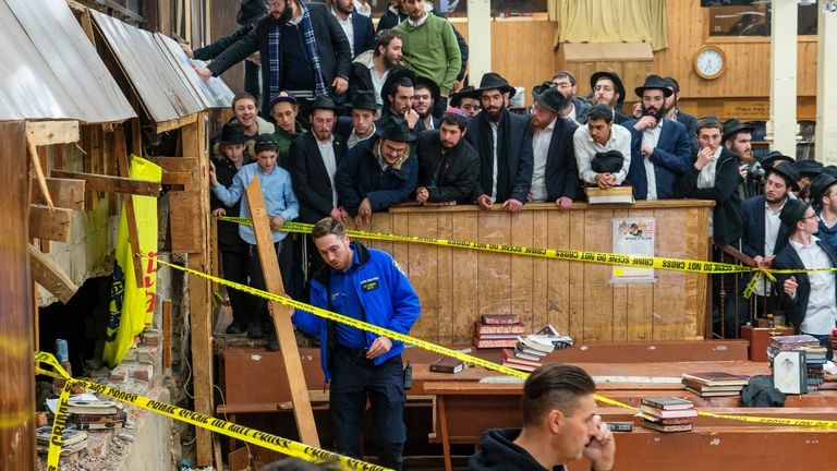 Hasidic Jewish students observe as law enforcement establishes a perimeter around a breached wall in the synagogue that led to a tunnel dug by students 
Pic:AP