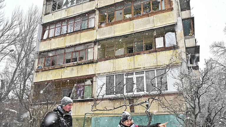 Volunteers talk next to an apartment building damaged in the strikes on Zaporizhzhia