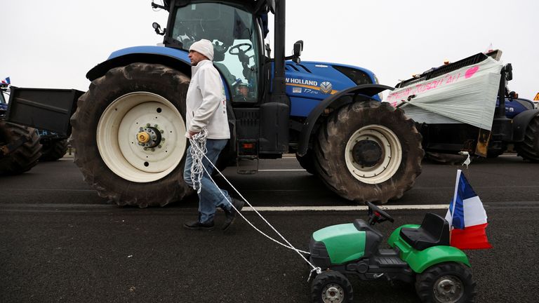 Farmer Vincent Guyot  walks with a toy tractor, during a blockade by farmers on the A4 in Jossigny.
Pic: Reuters