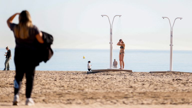 A fully-clothed woman looks on as another woman showers in her swimsuit in Valencia, Spain January 25, 2024 REUTERS/Eva Manez