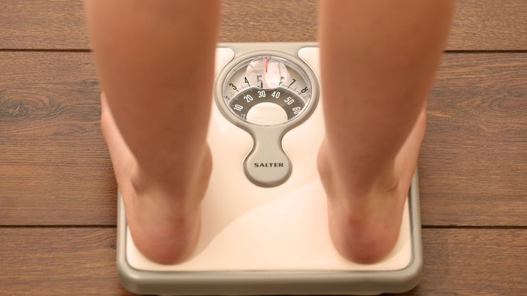模特摆拍的一张站在体重秤上的人的照片。图片标签、减肥、饮食、健康