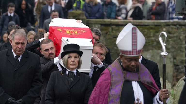 The coffin, draped in a Manchester United flag, is carried into the church 