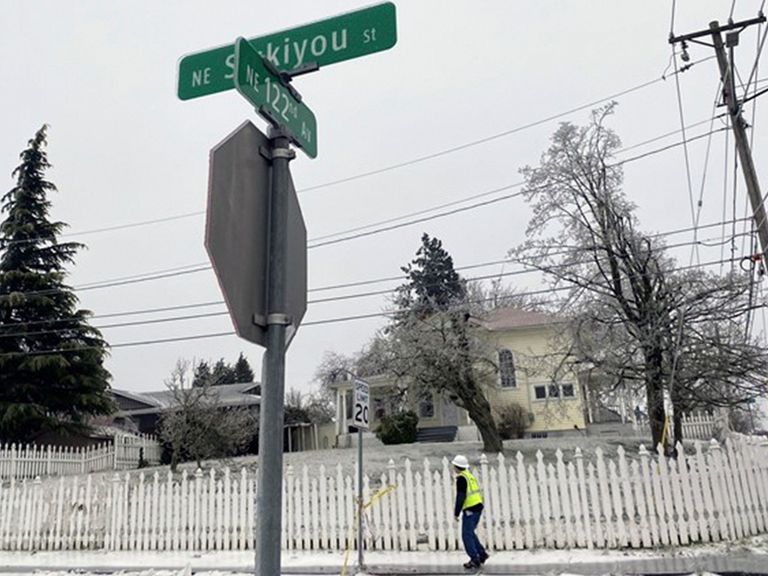 In this image made from video provided by KGW, police tape hangs from a speed limit sign on Wednesday, Jan. 17, 2024, in Portland, Ore., near the scene after a power line fell on a vehicle killing three people and injuring a baby during an ice storm. (Joe Raineri/KGW via AP)