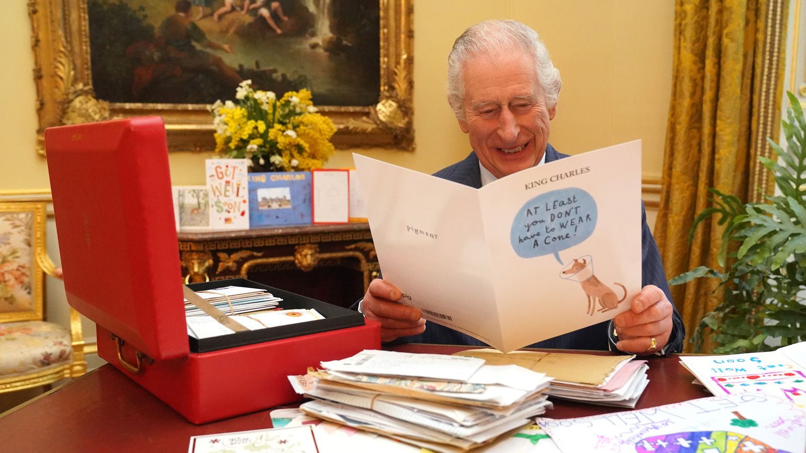 King Charles shown chuckling at get well card featuring dog in a head cone