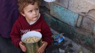 A Palestinian boy holds a can with cooked food. Pic: Reuters