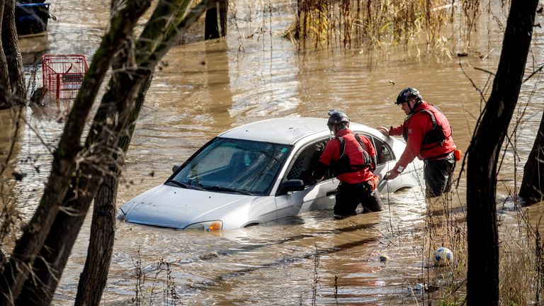 Rescuers go to a flooded car in San Jose. Pic: AP