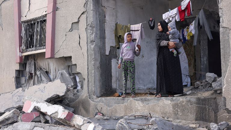 A Palestinian woman holds her child as she stands at a house damaged in Israeli strikes in Rafah. Pic: Reuters