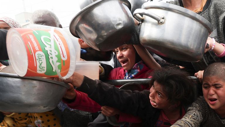 Palestinian children wait to receive food cooked by a charity kitchen, in Rafah, Gaza, on 13 February. Pic: Reuters