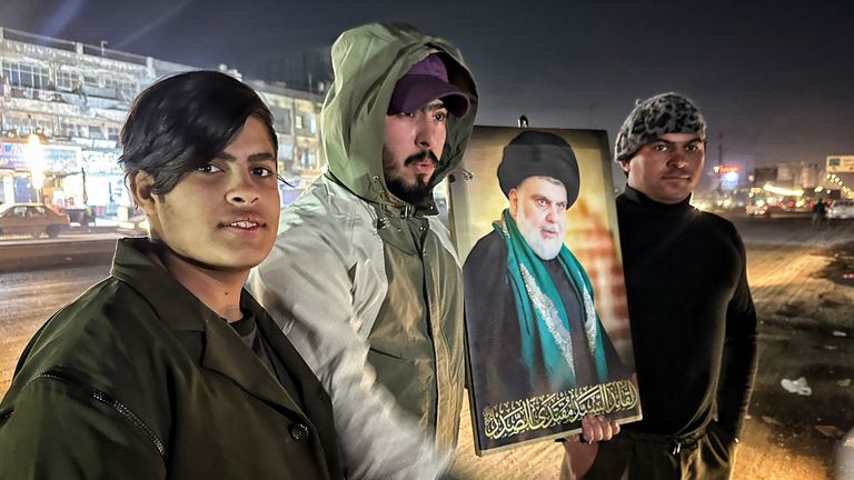 People at the scene of a US air strike in Baghdad, Iraq, carry an image of Muqtada al-Sadr, a prominent Iraqi Shia cleric. Pic: Sky News screengrab.