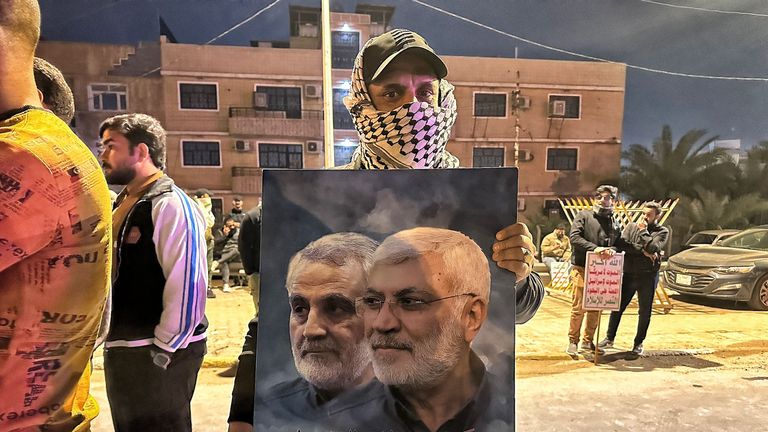 A person at the scene of a US air strike in Baghdad, Iraq, holds up an image of Qassam Soleimeini, a prominent IRGC officer assassinated in Baghdad in 2020. The guy on the right is Abu Mahdi al-Muhandis, deputy chief of PMF and head of Kataib Hezbollah in Iraq who was killed in the same strike as Qassam Soleimeini in 2020. Pic: Sky News screengrab