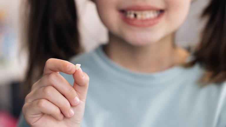 Little Girl Loosing her baby teeth. Little girl with milk temporary tooth. Happy child holding her fallen tooth in hand. Dental medicine or temporary teeth health care concept Pic: iStock/Mykola Pokhodzhay