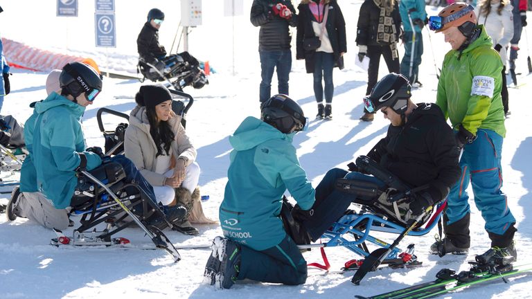 Meghan watches as Prince Harry sits in a para ski .
Pic: The Canadian Press /AP
