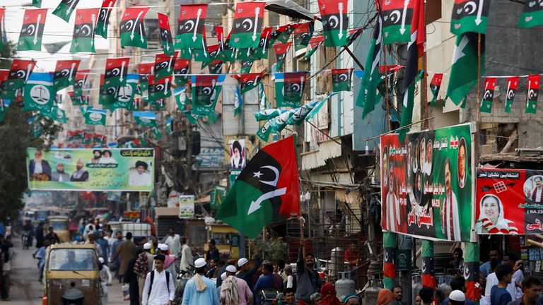People walk along a street decorated with campaign flags and posters of political parties, ahead of general elections, in Karachi, Pakistan January 23, 2024. REUTERS/Akhtar Soomro