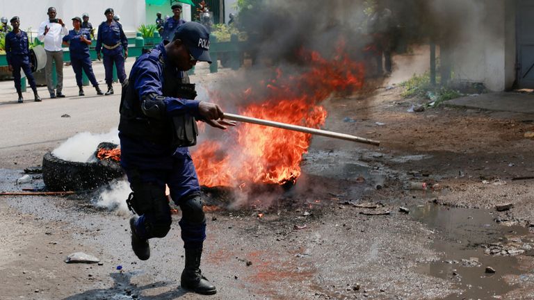 A police officer reacts in front of burning tyres after dispersing a protest. Pic: Reuters
