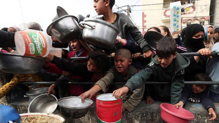 Palestinian children wait to receive food cooked by a charity kitchen amid desperate shortages of food in Rafah. Pic: Reuters