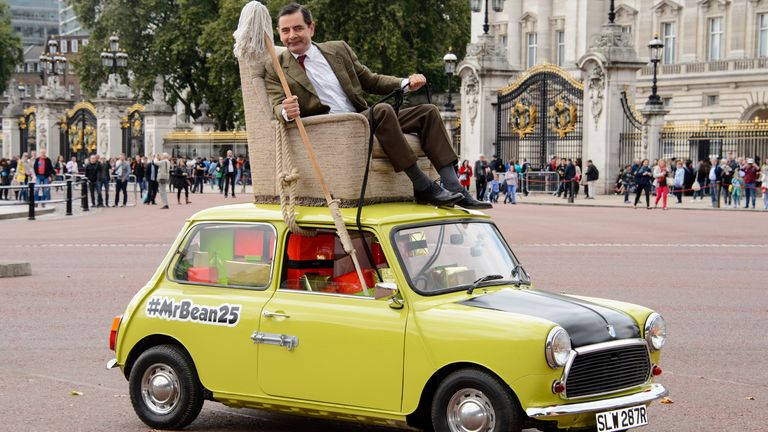 Atkinson pictured on top of Mr Bean&#39;s famous yellow Mini Cooper. Pic: AP