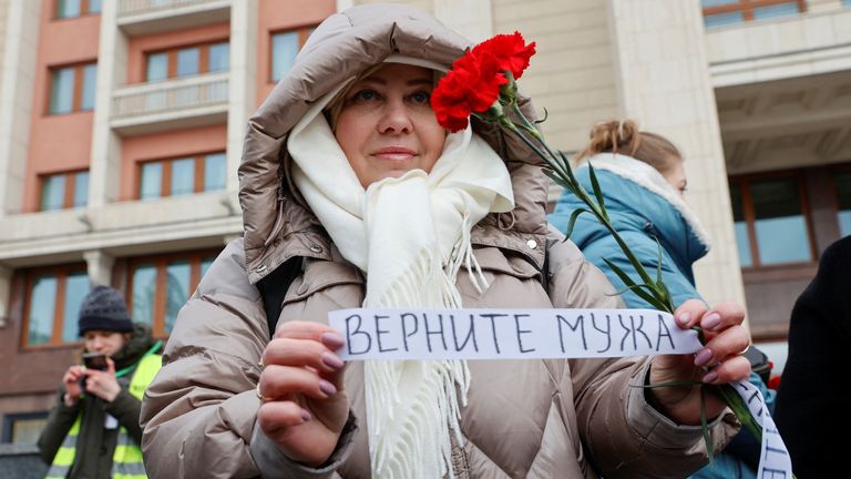 The wife of a mobilised serviceman, who joined the Russian armed forces involved in a military campaign in Ukraine, comes together with members of the women&#39;s movement "Way Home" to lay flowers at the Tomb of the Unknown Soldier by the Kremlin wall and to demand return of their husbands from Ukraine front, in Moscow, Russia, February 3, 2024. A slogan on the ribbon reads: "Bring husband back". REUTERS/Stringer