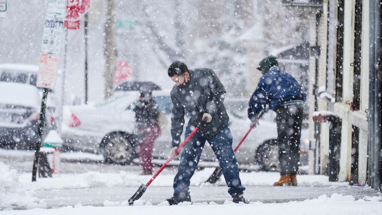 Люди расчищают тротуар во время зимней снежной бури в Филадельфии, вторник, 13 февраля 2024 года. Во вторник на некоторые районы северо-востока обрушилась снежная буря, из-за которой были отменены рейсы и школы, а люди были предупреждены о том, чтобы они держались подальше от дорог, в то время как в некоторых районах снежная буря была менее сильной. ожидается снег с изменением погодных условий.  (AP Photo/Мэтт Рурк)