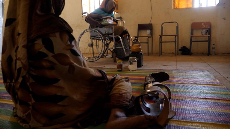 A woman sits on the floor next to a false leg in front of a woman in a wheelchair in Kassala, Sudan.